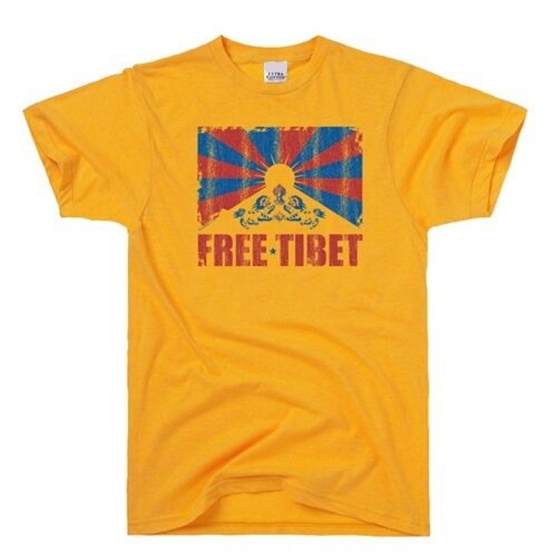 Pu&ograve; includere: Una maglietta gialla con un'immagine usurata della bandiera tibetana e il testo "FREE TIBET" stampato sul davanti.