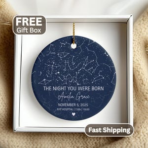 May include: A round navy blue ceramic ornament featuring a white star map constellation design. Text reads: THE NIGHT YOU WERE BORN, Amelia Grace, NOVEMBER 5, 2025, NYP HOSPITAL | 7.8lb | 18:00. A small white heart icon is centered at the bottom.