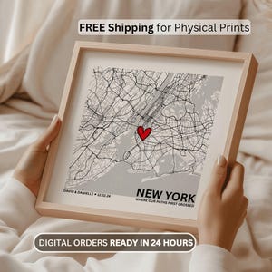 May include: Framed map print of New York City with a red heart marking a location. The map is in black and white, with the text "NEW YORK" and "WHERE OUR PATHS FIRST CROSSED". The frame is light wood. Text at the top says "FREE Shipping for Physical Prints".