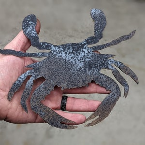 May include: A metal crab sculpture with a rustic, weathered finish. The crab is in a raised position with its claws extended.