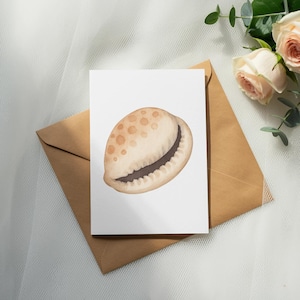 Puede incluir: Ilustración en acuarela de una concha marina sobre una tarjeta blanca. La concha es beige con manchas marrones y un interior oscuro. La tarjeta descansa sobre un sobre marrón, con rosas y vegetación en el fondo.