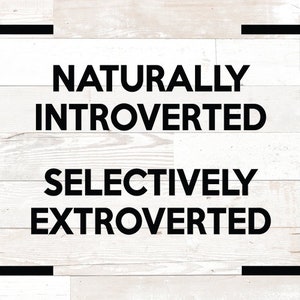 May include: Image with the text "NATURALLY INTROVERTED" above "SELECTIVELY EXTROVERTED" in bold black font. The text is centered on a white wooden plank background, framed by black corner brackets.