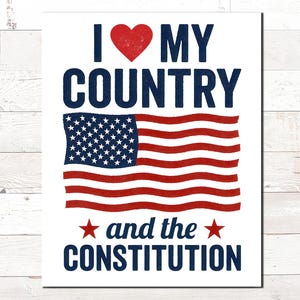 Może przedstawiać: Biały prostokątny nadruk z napisem "I ❤️ MY COUNTRY and the CONSTITUTION". Projekt zawiera czerwone serce, powiewającą amerykańską flagę i dwie czerwone gwiazdy. Tekst i flaga są w kolorze granatowym i czerwonym.