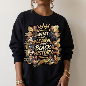 May include: Black sweatshirt featuring a gold crown and the text "What We Learn From Black History." The design includes portraits of historical figures. The sweatshirt is a crew neck style.