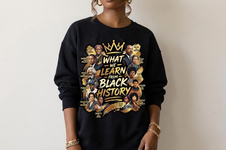 May include: Black sweatshirt featuring a gold crown and the text "What We Learn From Black History." The design includes portraits of historical figures. The sweatshirt is a crew neck style.