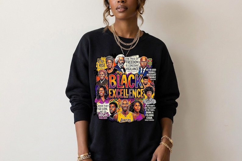 May include: Black sweatshirt featuring a colorful graphic with the words "BLACK EXCELLENCE" and portraits of notable figures. The design includes quotes and the Lakers logo. The sweatshirt is worn by a person.