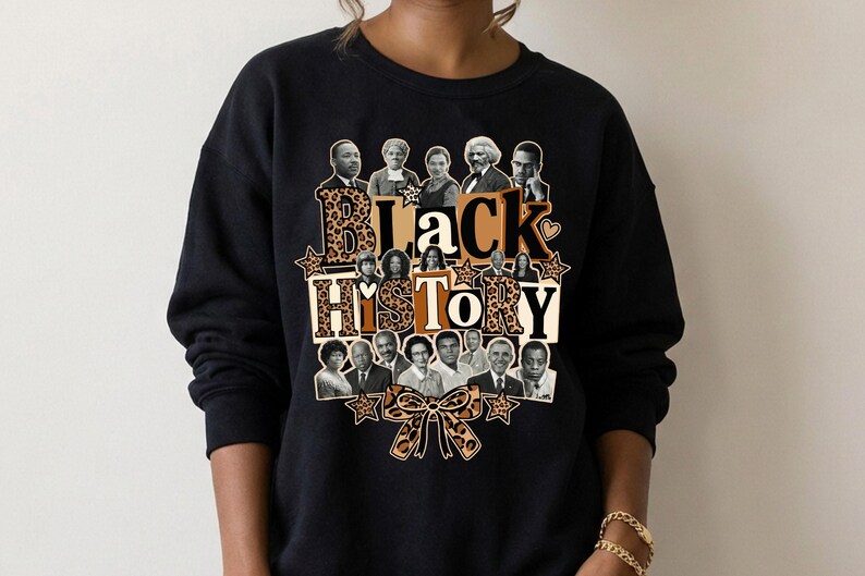 May include: Black sweatshirt featuring a graphic design with the words "Black History" in a mix of leopard print and solid colors. The design includes portraits of historical figures and a bow.
