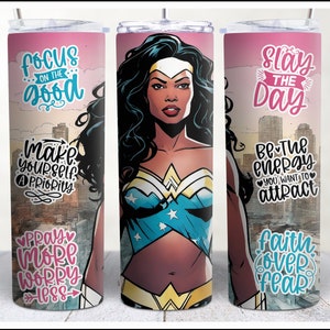 May include: Three stainless steel tumblers with colorful designs and inspirational quotes. The tumblers feature a woman superhero with a pink, blue, and white costume. The quotes are "Focus on the good", "Slay the Day", and "Pray More Worry Less".