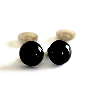 Peut inclure: Deux yeux de sécurité en plastique noir avec des rondelles argentées. Les yeux sont ronds et ont une finition brillante.