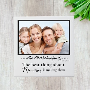 May include: A white framed photograph featuring a family of four smiling. The photograph is surrounded by a black border and includes the text "The Stockholm family Est 2014" and "The best thing about Memories is making them".