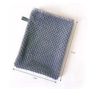 Può includere: Guanto da cucina in tessuto grigio testurizzato con un'ansa. Il telo misura 17 cm per 23 cm.