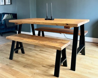 May include: A wooden dining table with black metal A-frame legs and a matching wooden bench. The table and bench are set against a teal wall with a light wood floor.