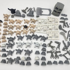 May include: A collection of unpainted miniature plastic gaming figures and components in various shades of gray, white, and tan. The set includes numerous small humanoid figures, weapon parts, mechanical arms, and structural pieces arranged on a surface.