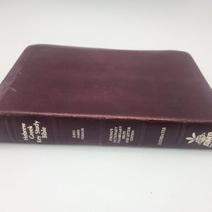 May include: A dark maroon hardcover book titled Hebrew Greek Key Study Bible, King James Version, Strong's Dictionary Vocabulary Helps Red Letter Edition, Zodhiates, AMG Publishers. The spine features gold text and a small logo of a globe.