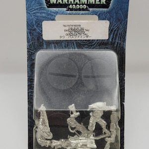 May include: A Warhammer 40,000 Tau Pathfinders miniatures set in a sealed plastic package. The package has a blue and silver design with the Warhammer logo and text in multiple languages.