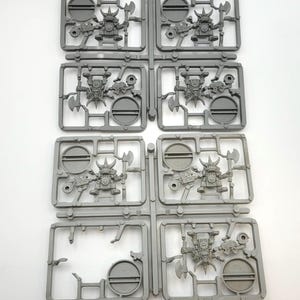 May include: Gray plastic miniatures on sprues. Each miniature is a fantasy character with an axe and a gun. The miniatures are in various poses, ready for assembly. The sprues are arranged in a grid pattern.