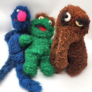 Könnte beinhalten: Eine weiße Keramik-Tasse mit schwarzem Henkel und dem Text "But First, Coffee" in schwarzer, handschriftlicher Schrift. Die Tasse steht auf einer weißen Oberfläche.