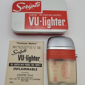 Może przedstawiać: Zestaw zapalniczki Scripto VU w stylu vintage, zawierający czerwono-białe metalowe pudełko, przezroczystą zapalniczkę z widocznym dopływem paliwa i instrukcję. Zapalniczka ma srebrną górę i czerwone akcenty, z nadrukiem "ALLSTATE TRUCK TIRES".