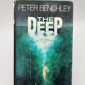 May include: Vintage paperback book titled "The Deep" by Peter Benchley. The cover features a teal and dark blue underwater scene with a diver. Text includes "A new novel by the author of Jaws."