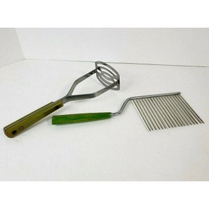 Può includere: Due utensili da cucina vintage con manici verdi. Uno schiacciapatate con una struttura in metallo e un pettine per torte con una lama di metallo lunga e sottile.