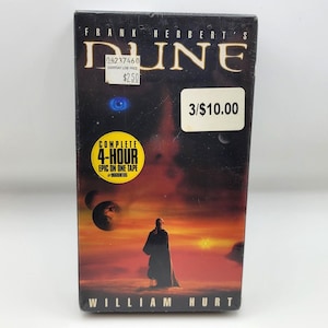 May include: A VHS tape of Frank Herbert's "Dune" featuring William Hurt. The cover art depicts a figure in a cloak against a red and orange sky with planets. The tape includes the text "COMPLETE 4-HOUR EPIC ON ONE TAPE".