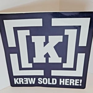 May include: A black and white sticker with a white letter K inside a white maze design. The text "Krew Sold Here!" is printed below the maze.