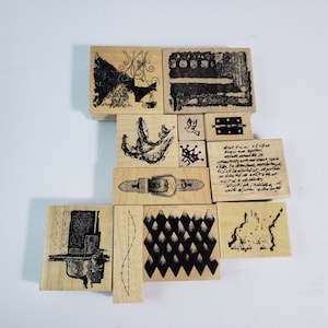 Puede incluir: Una colección de sellos de madera con varios diseños, incluyendo formas abstractas, una hebilla de cinturón, una corona y texto. Los sellos están dispuestos sobre una superficie blanca, mostrando sus diversos patrones y texturas.