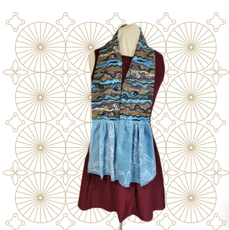 May include: A blue and brown patterned scarf with a blue and white apron. The apron has a ruffled bottom and a white design.