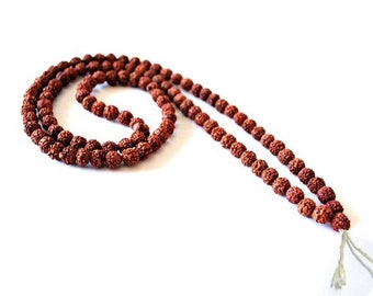 May include: A brown mala bead necklace made of rudraksha seeds. The necklace is approximately 108 beads long and has a tassel at the end.