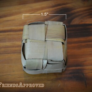 May include: A woven, square-shaped, light brown basket made of natural materials. The basket is 1.5 inches wide.