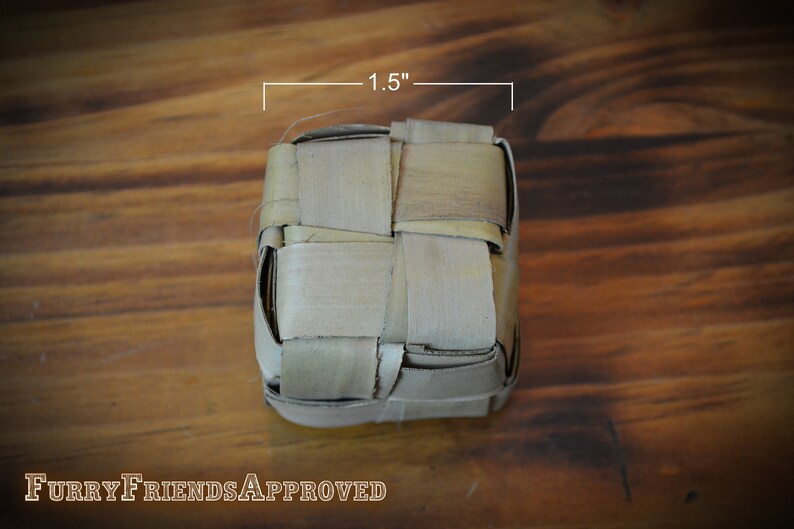 May include: A woven, square-shaped, light brown basket made of natural materials. The basket is 1.5 inches wide.