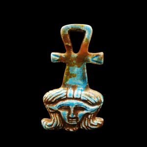 May include: A blue and brown Ankh pendant with a face at the base. The pendant has a loop at the top, a crossbar, and a face with blue details. The colors are a mix of blue, brown, and gold, with a glossy finish.