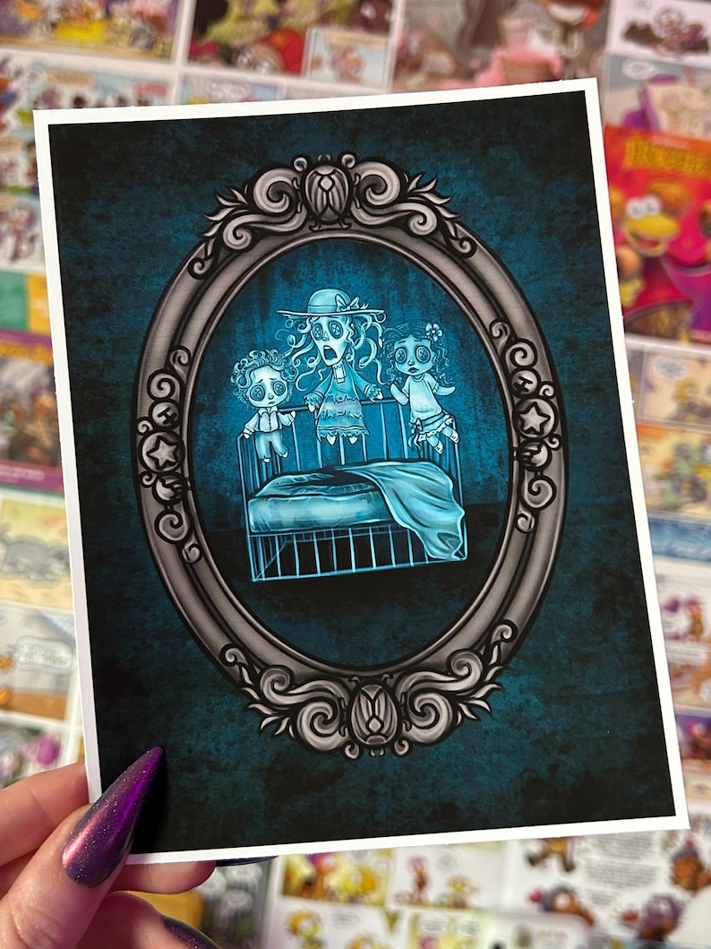 May include: A vintage-style silver frame with an ornate design surrounds a blue and white illustration of three ghostly figures in a crib. The figures are all wearing white clothing and have large, wide eyes. The illustration is set against a dark blue background.