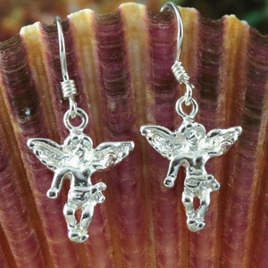 K&ouml;nnte beinhalten: Ein Paar silberne Ohrh&auml;nger mit einem Cherub-Design. Die Cherubim haben Fl&uuml;gel und stehen mit ausgestreckten Armen.