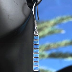 May include: Silver dangle earrings with a blue opal bar pendant. The bar is made up of multiple small square opals.