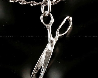Op de afbeelding: Een zilveren ketting met een hanger in de vorm van een schaar. De ketting is delicaat.