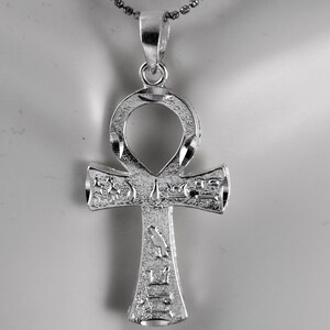 May include: Silver Ankh pendant with intricate details and hieroglyphics. The pendant is on a silver chain.