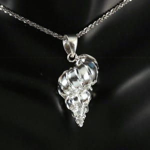 May include: A silver necklace with a detailed seashell pendant. The pendant is made of multiple layers of silver, creating a realistic seashell design.