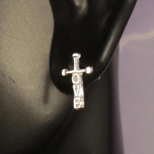 May include: Silver cross earrings with the word "LOVE" spelled vertically down the center of the cross.