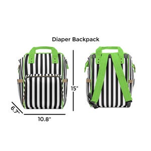 Puede incluir: Mochila para pa&ntilde;ales a rayas blancas y negras con correas verdes. La mochila mide 38 cm de alto, 27 cm de ancho y 17 cm de profundidad.