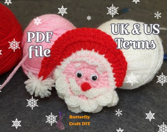 May include: A crocheted Santa Claus ornament with a red hat, white beard, and pink cheeks. The ornament is surrounded by balls of yarn in pink, white, and red. The text "PDF file" and "UK & US Terms" is visible in the image.