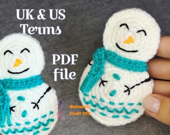 May include: Two white crocheted snowmen with black eyes and smiles, orange noses, and teal scarves. The snowmen have teal embroidered details on their bodies. The text "UK & US Terms PDF file" is visible in the image.