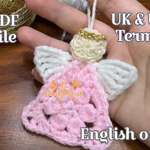 May include: A handmade crochet angel ornament with a cream-colored head and white wings. The angel's dress is pink, and it has a gold halo. The image also includes the text "PDF file", "UK & US Terms", and "English only".