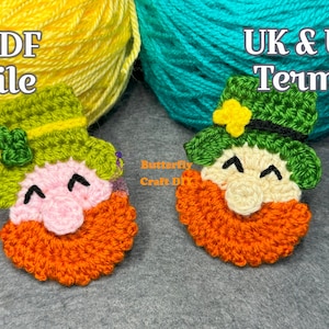 May include: Two crocheted leprechaun figures with green hats, white faces, and orange beards. The leprechauns are sitting on a gray surface. The text "UK & US Terms" is visible in the background.