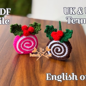 Puede incluir: Dos adornos navideños de ganchillo. Uno es rosa con un diseño de remolino blanco, cubierto con hojas verdes y bayas rojas. El otro es marrón con un remolino blanco, hojas verdes y un corazón rojo. El texto "PDF file" y "English only" son visibles.