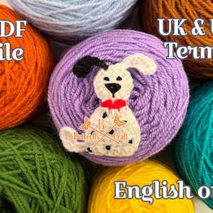 May include: A crocheted dog with black spots, a red collar, and black ears is centered on a purple yarn ball. The image is surrounded by various colored yarn balls, including orange, green, blue, and yellow. Text includes "PDF file" and "English only".