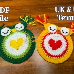 May include: Two crocheted owl coasters with heart designs. One coaster is green and yellow, the other is yellow and red. The text "PDF file" and "UK & US Terms" is visible in the image.