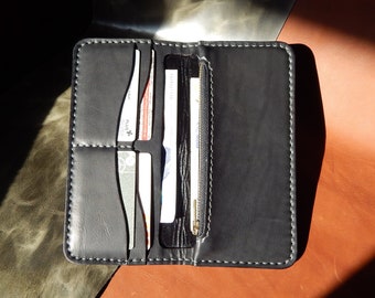 May include: A black leather wallet with a zippered pocket and multiple card slots. The wallet is open and has several cards inside.