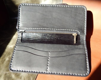 May include: A black leather wallet with a zippered compartment and multiple card slots. The wallet is open and the interior is visible.