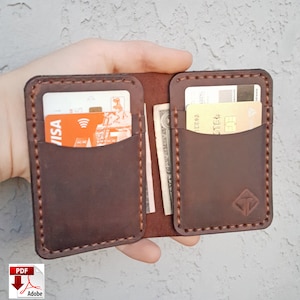May include: A brown leather wallet with two card slots and a cash pocket. The wallet is open and has a credit card and cash inside.
